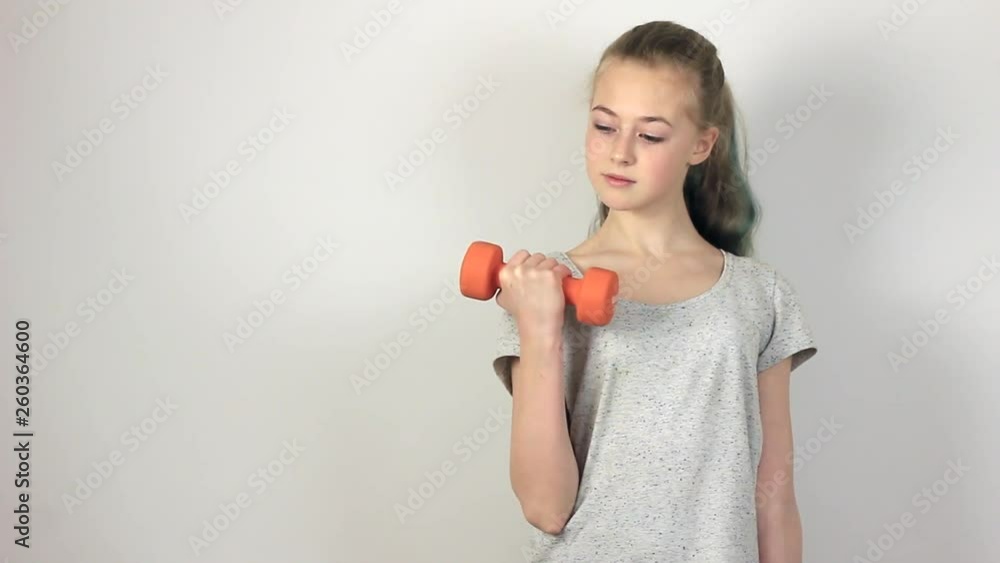 Attractive girl doing exercises with dumbbells. Copy space on a gray background. Fitness and healthy sports lifestyle. Attractive girl doing exercises with dumbbells. Copy space on a gray background. Fitness and healthy sports lifestyle.