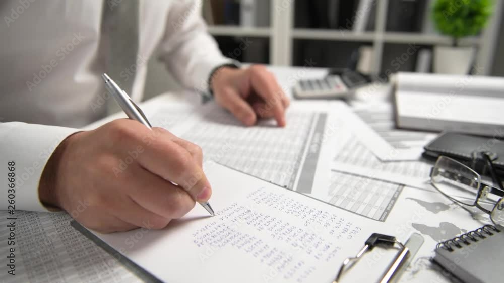 Businessman working at office and calculating finance, reads and writes reports. Business financial accounting concept. Businessman working at office and calculating finance, reads and writes reports. Business financial accounting concept.