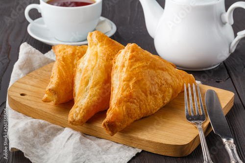 Puff pastry triangles filled with feta cheese and spinach on wooden table photo