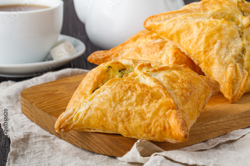Puff pastry triangles filled with feta cheese and spinach on wooden table