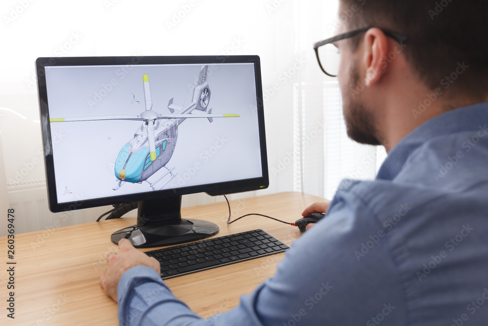 Engineer, Constructor, Designer in Glasses Working on a Personal Computer. He is Creating, Designing a New 3D Model of Helicopter in CAD Program. Freelance Work Engineer, Constructor, Designer in Glasses Working on a Personal Computer. He is Creating, Designing a New 3D Model of Helicopter in CAD Program. Freelance Work