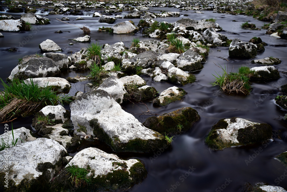 steine im fluss werden umspült von wasser und sind mit gras bedeckt steine im fluss werden umspült von wasser und sind mit gras bedeckt