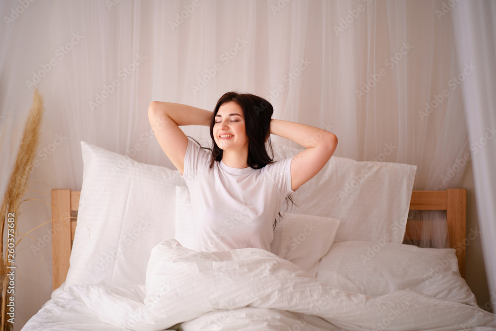 woman awakening stretching in bed in early morning