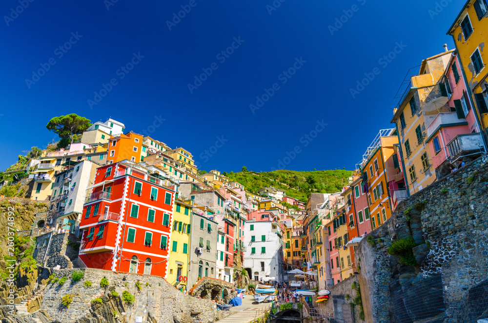 Riomaggiore traditional typical Italian fishing village in National park Cinque Terre, colorful multicolored buildings houses on hill, clear blue sky copy space background, La Spezia, Liguria, Italy