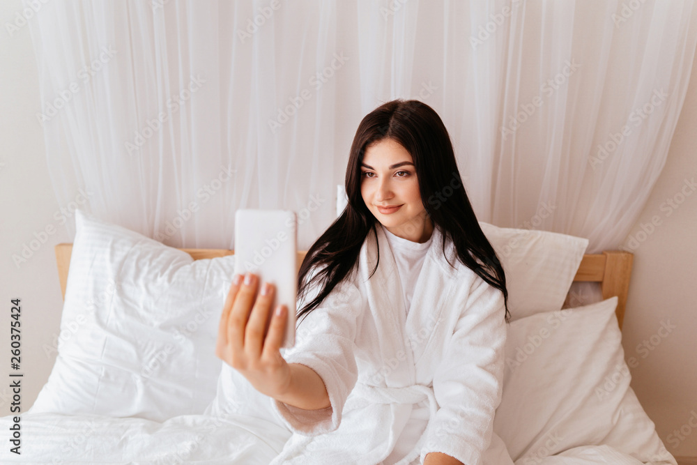 Woman taking selfie with smart phone in hotel room Woman taking selfie with smart phone in hotel room