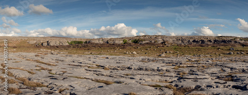 Panorama image of Terrain in Burren national park, county Clare, Ireland, stone surface and cloudy blue sky.