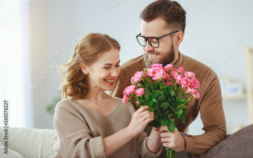 happy loving   couple. husband gives his wife flowers at home    .