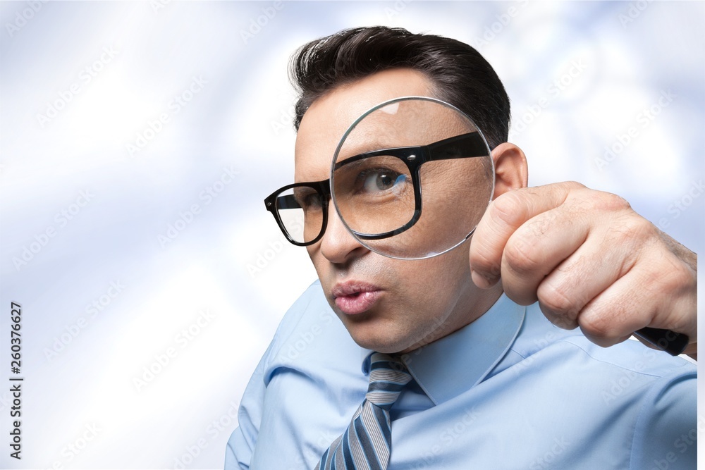 Young business man in suit and glasses holding magnifying glass Young business man in suit and glasses holding magnifying glass