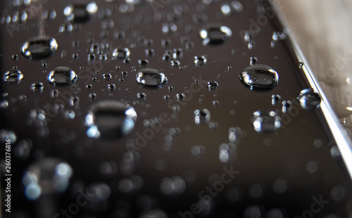 Back side of waterproof smartphone covered with drops of water
