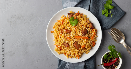 Ταπετσαρία Traditional asian dish - pilaf from from rice, vegetables and meat in a plate on gray background