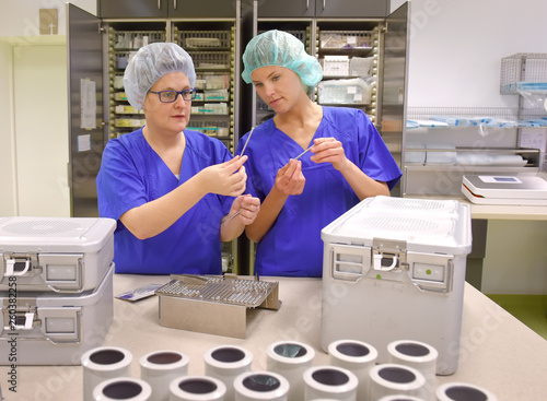 Two women are seen working as medical hygiene  workers. They are dressed in medical hygiene  clothing. They are seen carrying out hygiene  disinfecting and sterilization tasks.