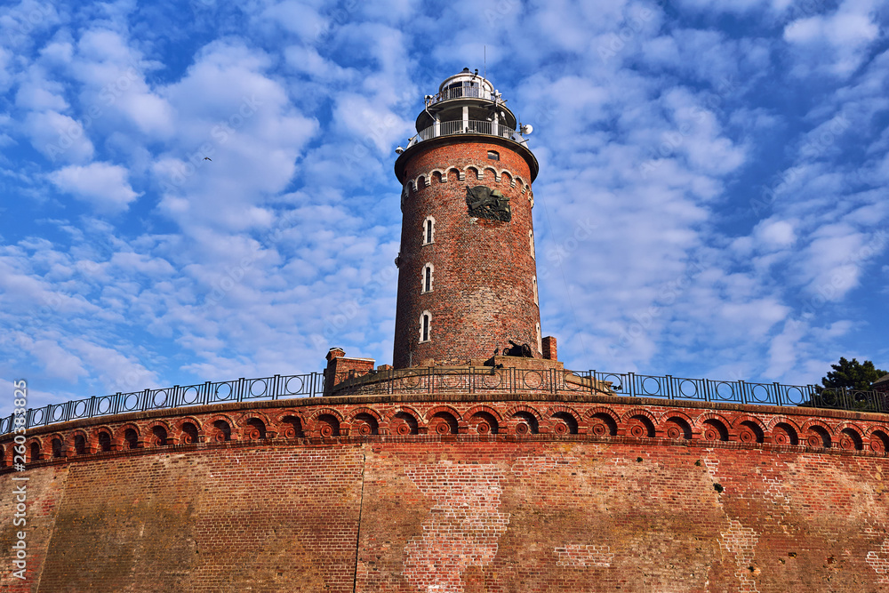 A red brick lighthouse at the entrance to the port in the city of Kolobrzeg.