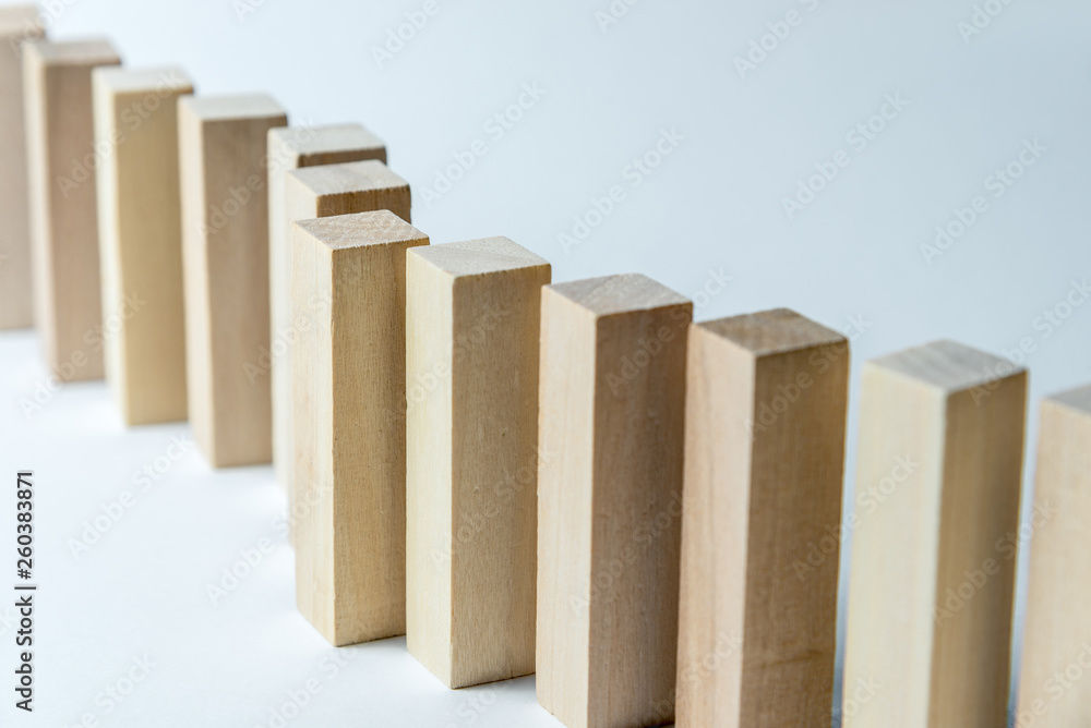 A long curved line of wooden cubes, as a symbol of a queue, competition for a position or team, on a uneven white background. Horizontal frame A long curved line of wooden cubes, as a symbol of a queue, competition for a position or team, on a uneven white background. Horizontal frame