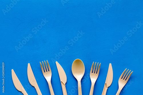 Plastic utilization concept with flatware on blue background top view mock up photo