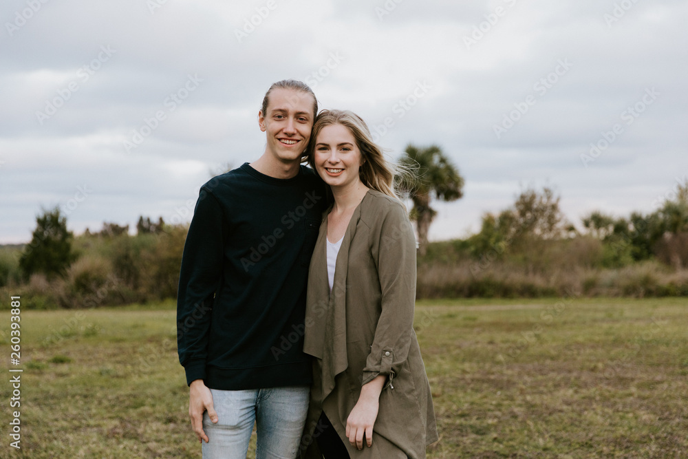 Young Couple in Love Running in a Big Open Outdoor Field in the Spring Holding Hands and Laughing