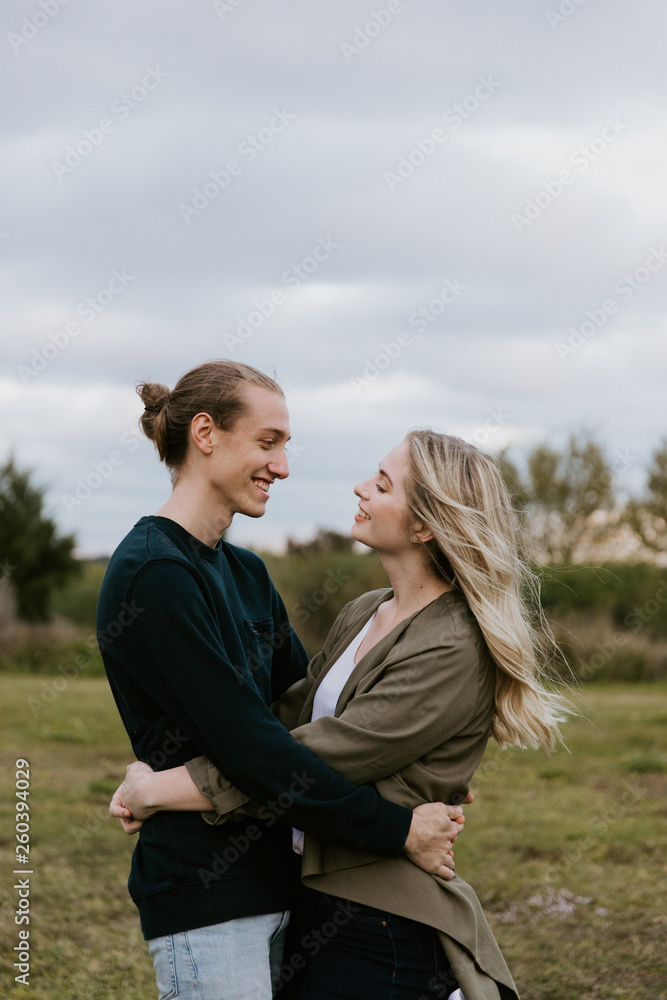 Young Couple in Love Running in a Big Open Outdoor Field in the Spring Holding Hands and Laughing