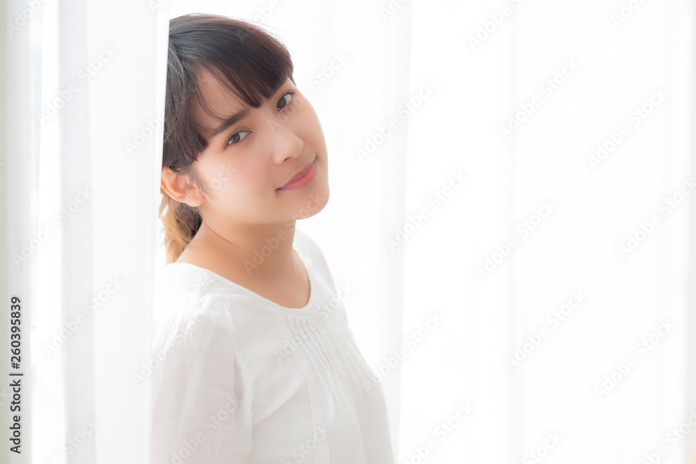 Portrait of beautiful young asian woman standing the window and smile while wake up with sunrise at morning, girl happy with freshness and cheerful, lifestyle and relax concept. Portrait of beautiful young asian woman standing the window and smile while wake up with sunrise at morning, girl happy with freshness and cheerful, lifestyle and relax concept.