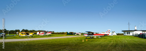 Panorama of rows of single engine planes next to a runway