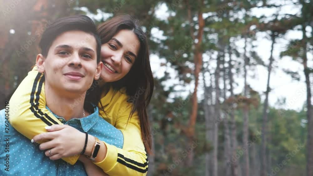 Hilarious young man bringing his cutie girl on his back in a pine forest in slo-mo Hilarious young man bringing his cutie girl on his back in a pine forest in slo-mo