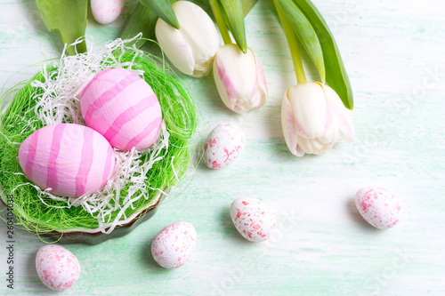 Easter greeting with white tulips and pink eggs in the nest.