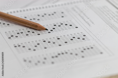 Fotografie Standardized test exam multiple carbon paper form with gray black answers sheet bubbled and pencil resting on university classroom