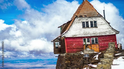 4K Timelapse of the Abandoned Chacaltaya Ski Resort Hut on the Edge of a Cliff with Clouds Passing Behind the Red House. photo