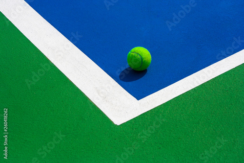 Green ball falling on floor nearly white lines of outdoor blue tennis hard court in public park. (Selective focus) © Angkana