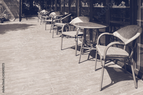 Abstract Black and White image of row of table and chair place on wooden terrace outside of restaurant or coffee cafe.