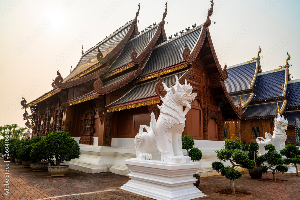 Fototapeta premium Beautiful Lanna style wooden building with white singha statues at a Buddhist temple in Thailand.