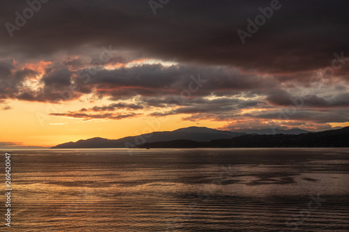 Sunset over the sea with mountains in the back