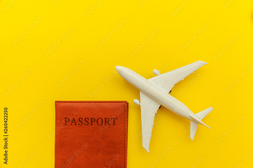 Travel by plane vacation summer weekend sea adventure trip journey ticket tour concept. Minimal simple flat lay with plane and passport on yellow trendy modern background. Tourist essentials