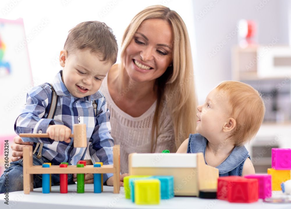 babysitter and children playing together in nursery or day care centre babysitter and children playing together in nursery or day care centre