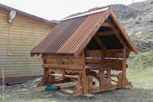 wooden arbor for rest with a roof, a table and benches