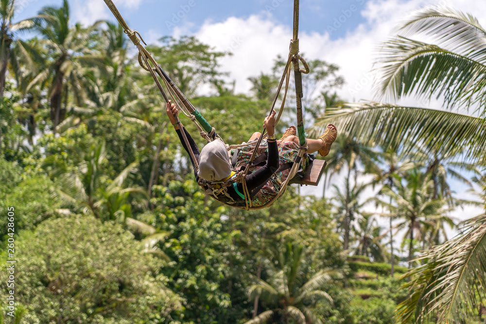 Asian girl swinging a swing in jungle on rice terraces, island Bali, Ubud, Indonesia