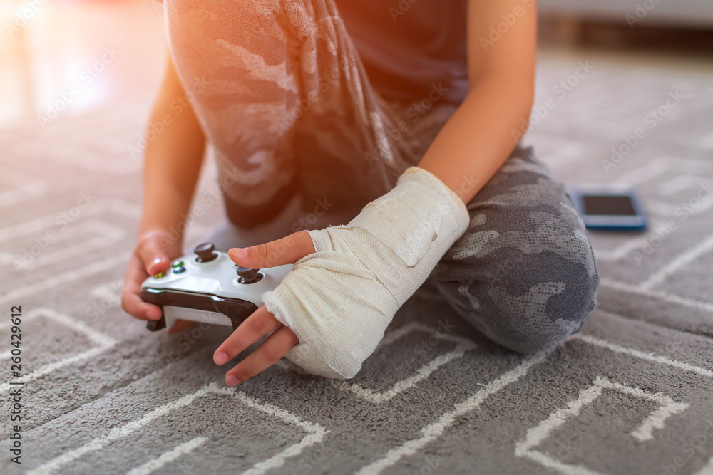 boy with injury at home. yonge video gamers hands using a gamepad Stock