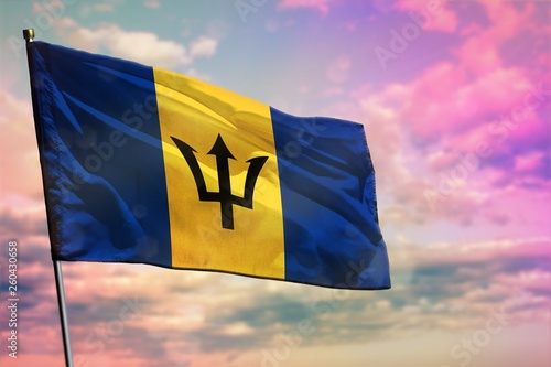 Fluttering Barbados flag on colorful cloudy sky background. Prosperity concept.