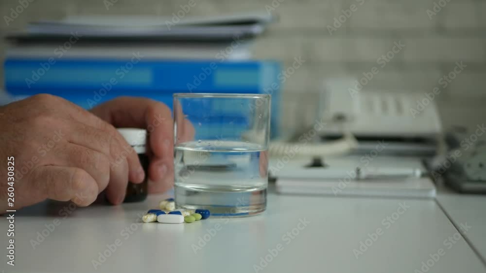 Man in Office Preparing for a Medical Treatment Taking Medical Pills with Water Man in Office Preparing for a Medical Treatment Taking Medical Pills with Water