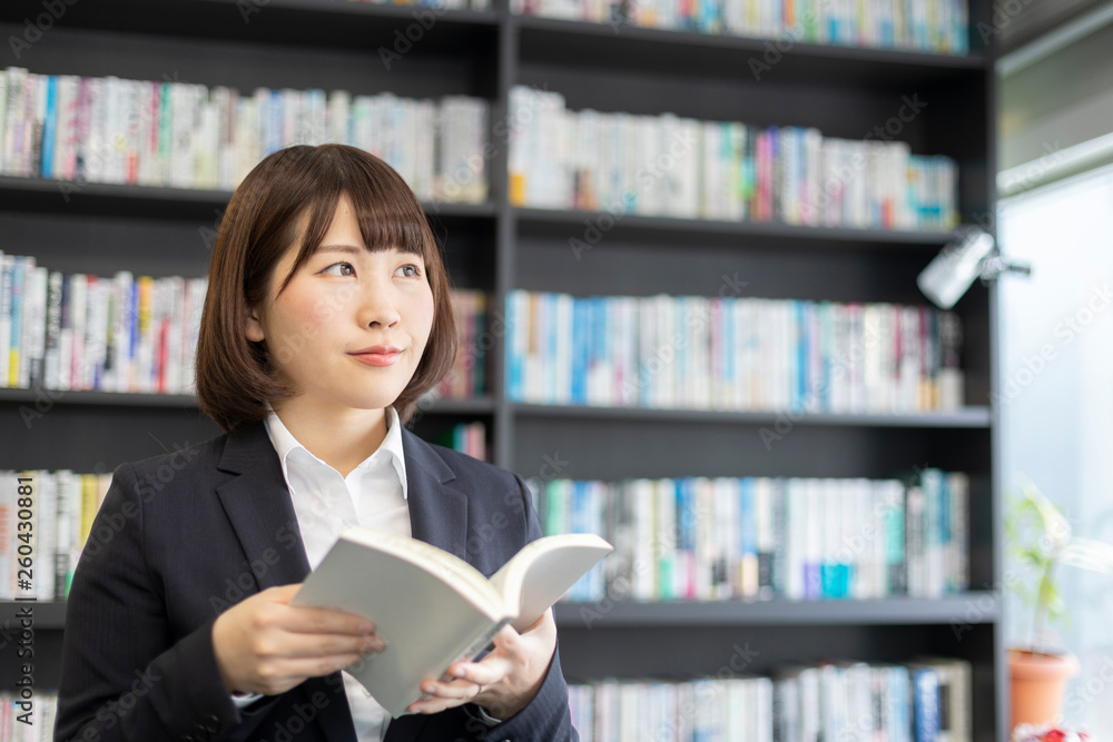 本棚を前に本を読む女性 本棚を前に本を読む女性