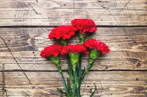 Red carnations on wooden background with copy space. Mother's Day card, Valentine's day.