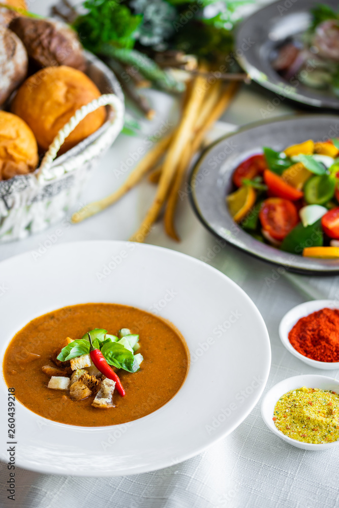 Mexican lunch, gazpacho soup with crackers and hot peppers in a white plate. tomato soup with vegetables. mexican soup. Puree soup tomato with croutons. Diet menu. tomato soup in a white plate Mexican lunch, gazpacho soup with crackers and hot peppers in a white plate. tomato soup with vegetables. mexican soup. Puree soup tomato with croutons. Diet menu. tomato soup in a white plate