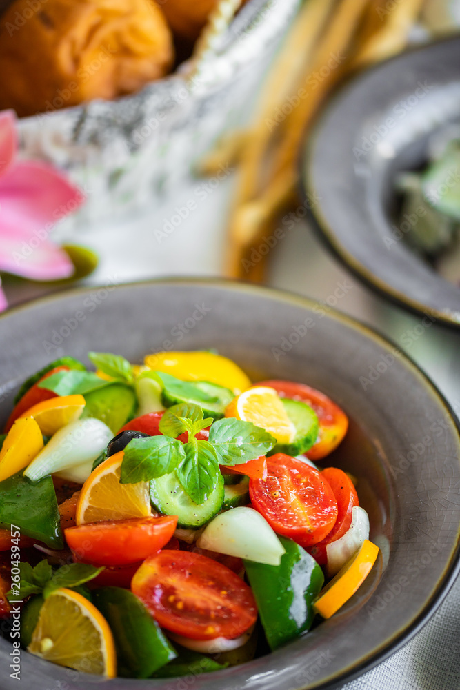 fresh salad of tomato cucumber pepper onion lemon and greens. healthy salad with fresh ripe summer vegetables fresh salad of tomato cucumber pepper onion lemon and greens. healthy salad with fresh ripe summer vegetables