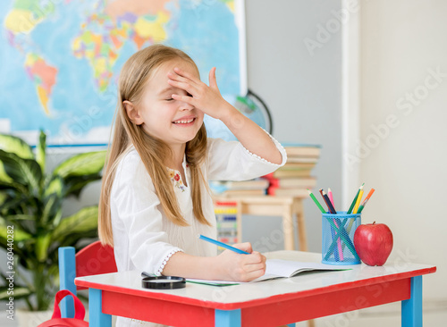Little smiling blond girl made a mistke writing in the school classroom