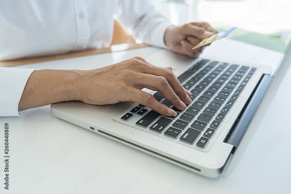 Young woman holding credit card and using laptop computer. Online shopping concept Young woman holding credit card and using laptop computer. Online shopping concept