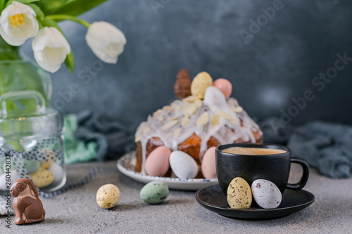 Fragrant cup of coffee and Easter orthodox sweet bread, kulich and colorful quail eggs with willow branches. Holidays breakfast concept with copy space. Retro style.