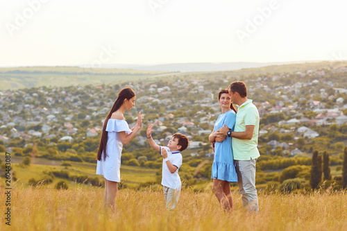 Happy family playing fun on the field at sunset.