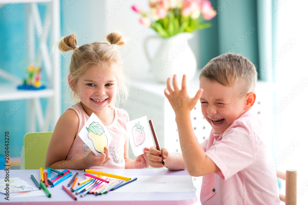 Fototapeta premium Little children play and draw with colorful pencils