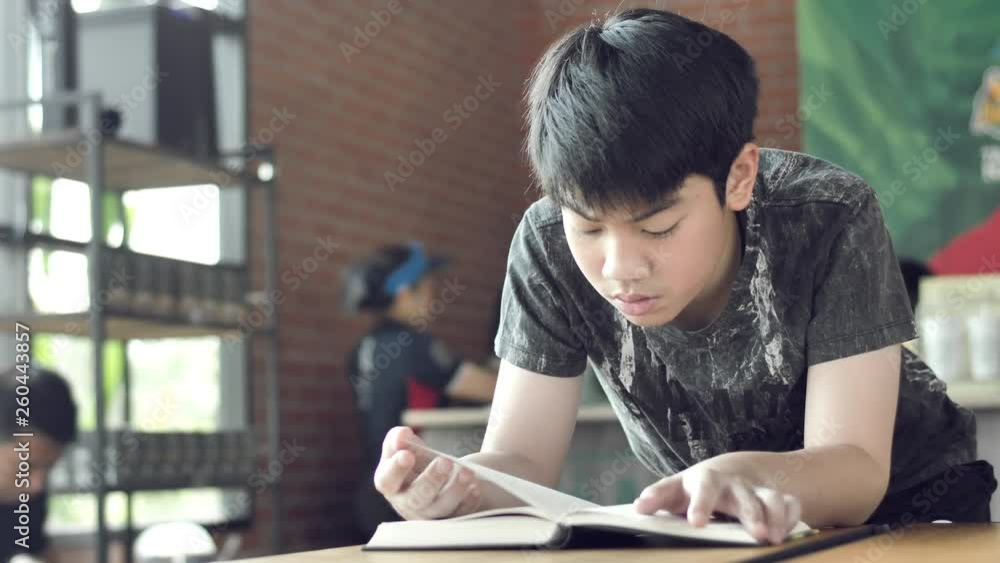 Asian cute boy read books while waiting for their mothers to buy drinks in the cafe. Asian cute boy read books while waiting for their mothers to buy drinks in the cafe.