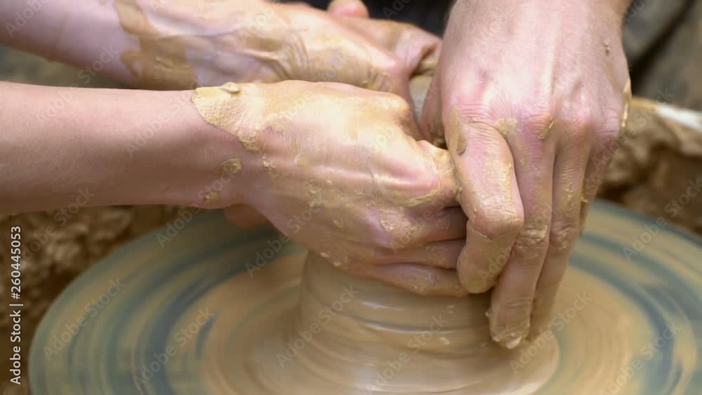 Two intertwined hands form a pot of clay on a potter's wheel. A male hand helps a woman's hands shape a clay shape. Two intertwined hands form a pot of clay on a potter's wheel. A male hand helps a woman's hands shape a clay shape.