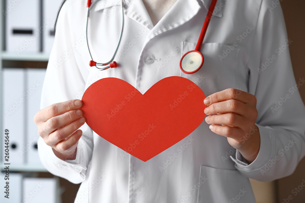 Female doctor with paper heart in clinic, closeup Female doctor with paper heart in clinic, closeup