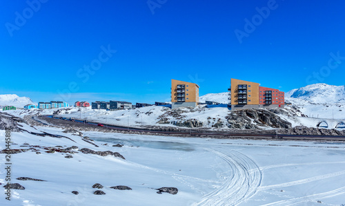 Inuit multistory houses of Nuuk city on the rocks with mountains in the background, Greenland photo